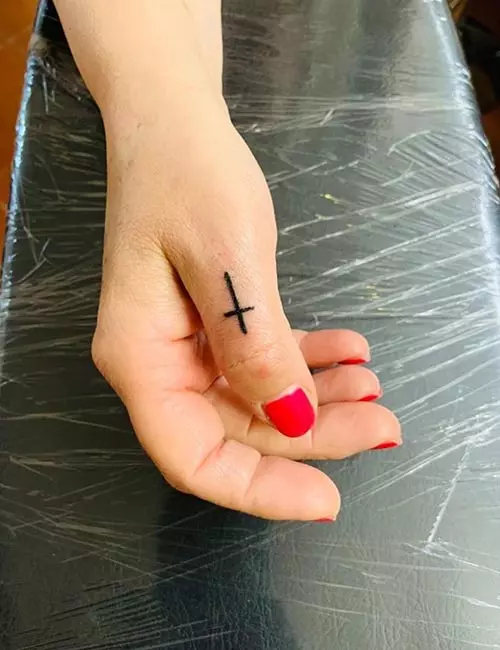 Small cross symbol tattoo design on finger