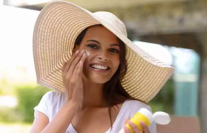 A woman applying sunscreen to her face.