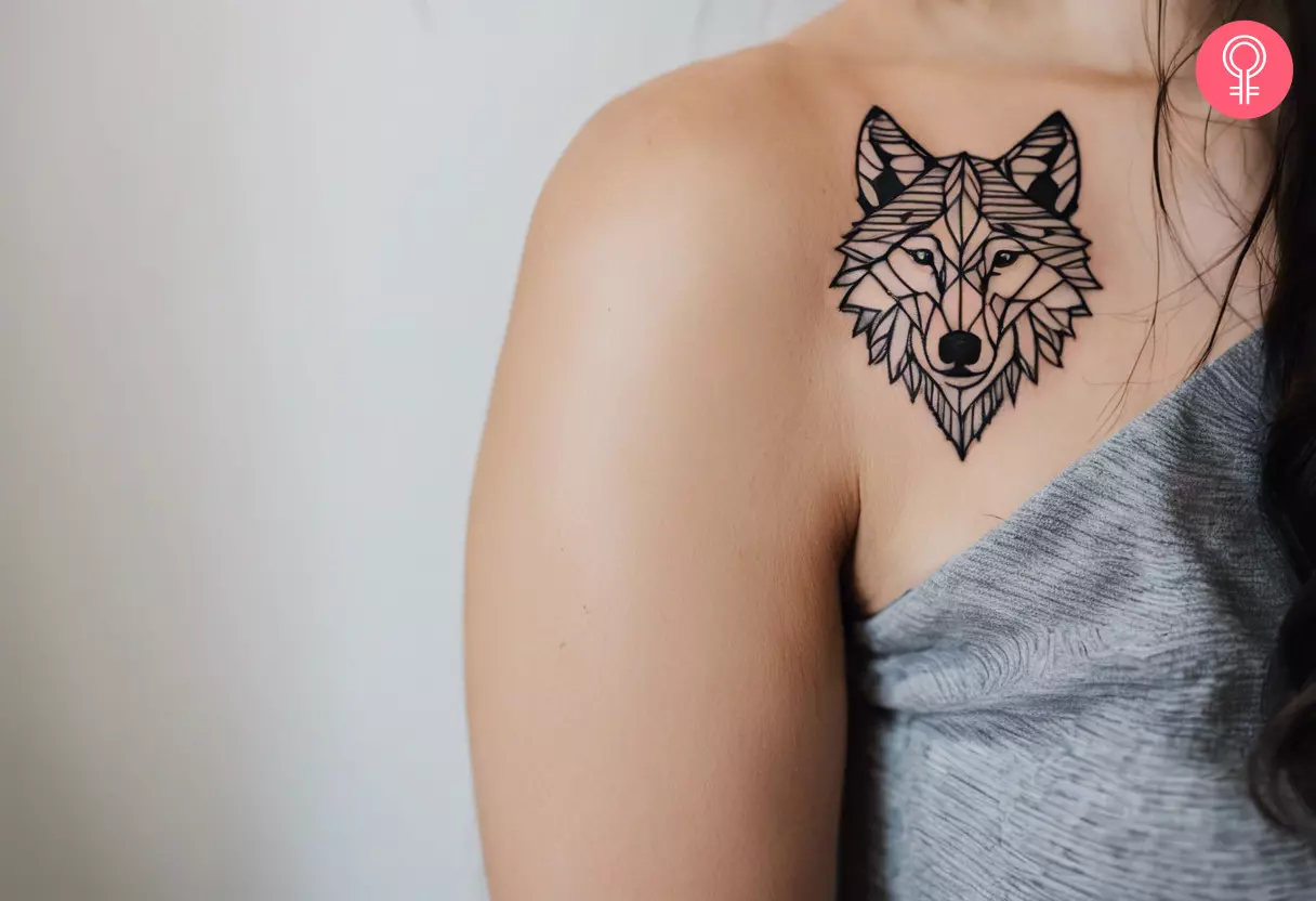 A minimalist wolf head tattoo on the shoulder