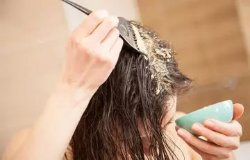 Woman applying banana and avocado hair mask