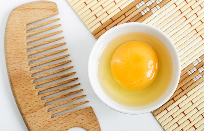 A bowl containing a raw egg and a comb to spread it evenly in the hair