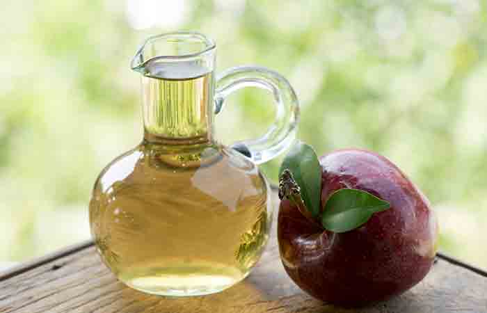 Flask of apple cider vinegar with an apple