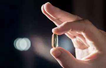 Woman holding vitamin e capsule