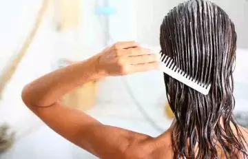 Woman applying conditioner with comb