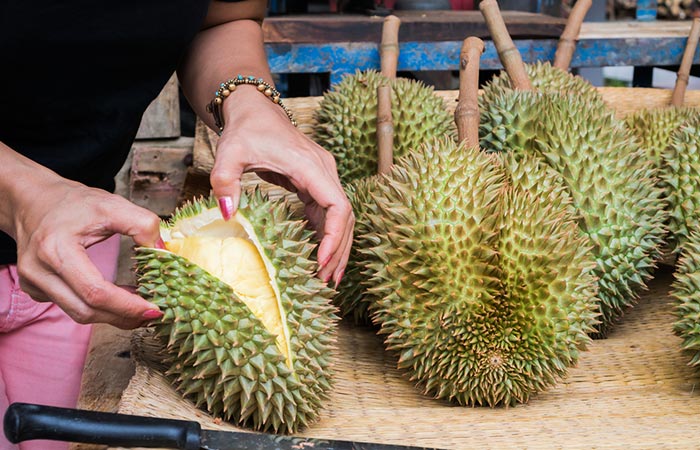 Person cutting durian fruit