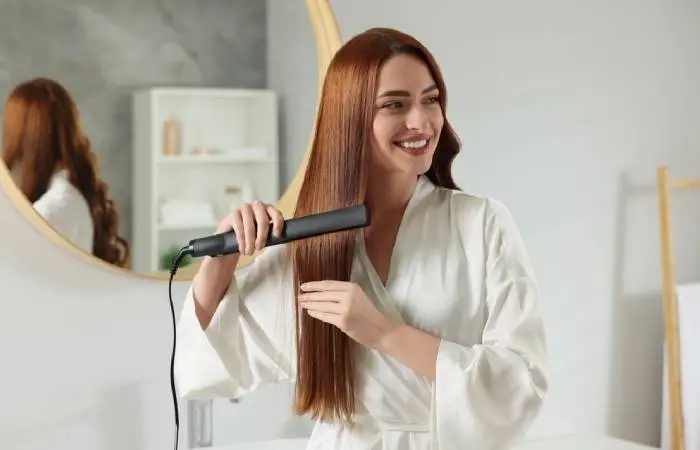 A woman straightening her long hair