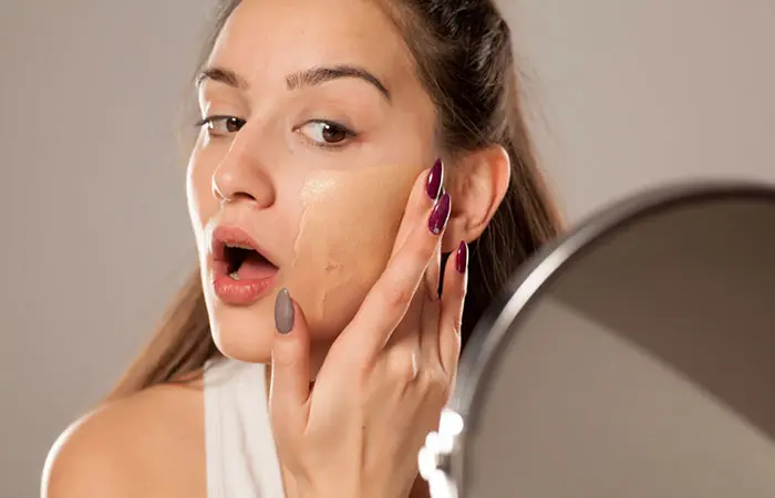 Woman applying excess foundation on her face