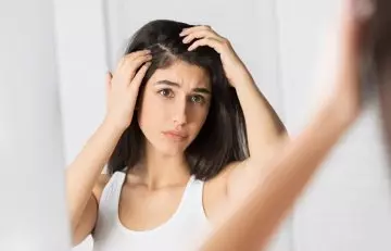 Girl looking at her hair flakes in the mirror 