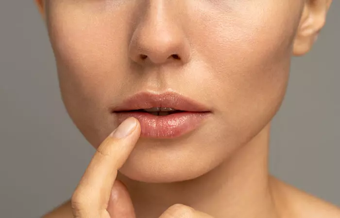 Woman applying mango seed butter to her dry lips