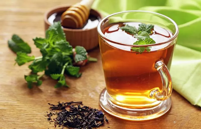 A cup of peppermint tea with the ingredients used to make it