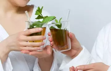 Two friends clink their glasses of peppermint tea