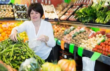 Woman selecting fresh green peas at grocery store