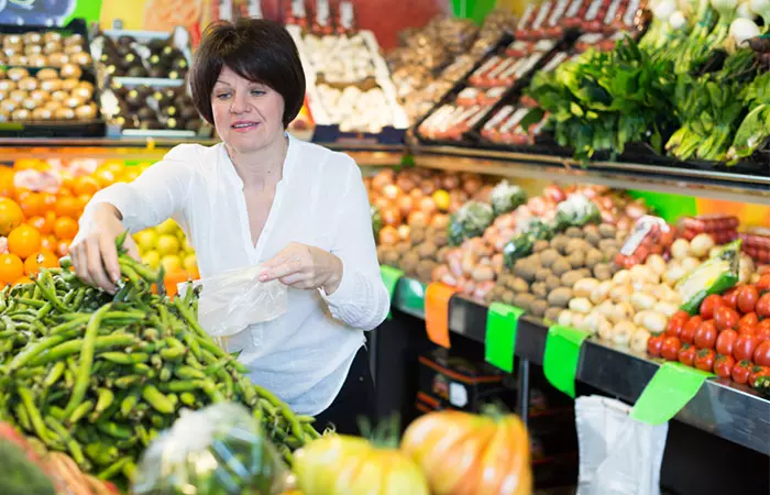 Woman selecting fresh green peas at grocery store