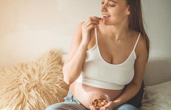 Pregnant woman at home eating soaked almonds
