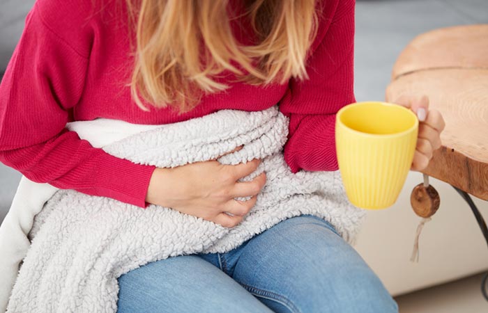 Woman having a mug of peppermint tea to minimize menstrual cramps.