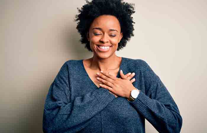 Smiling woman with hands over her heart 
