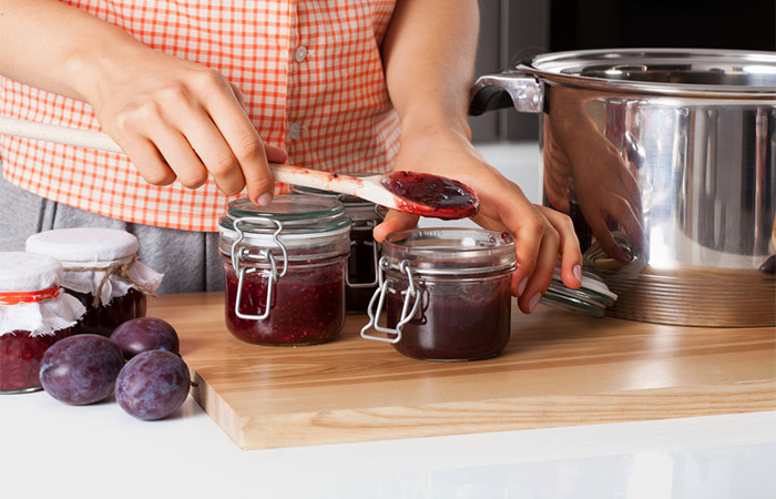 Woman uses plums to prepare jam.