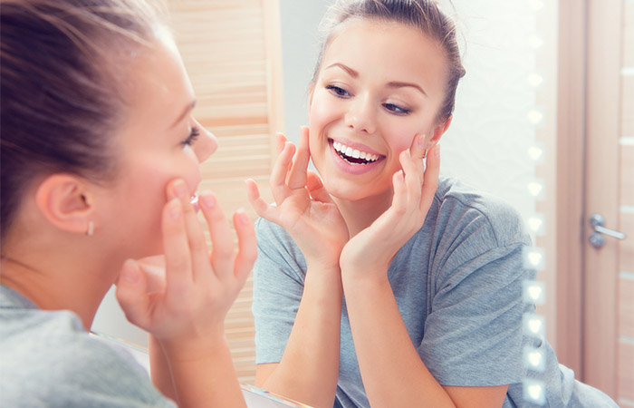 Woman looking at her radiant skin in the mirror