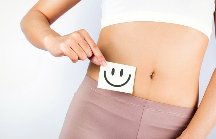 Woman holding a smiley near her tummy to concur green bell peppers may help improve digestive functions