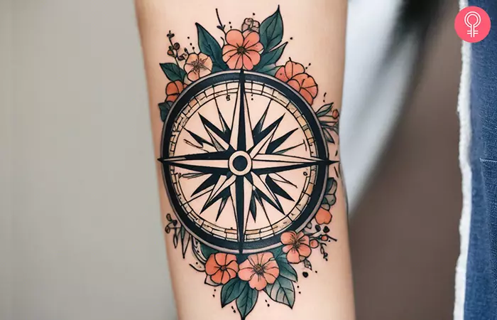 A woman with a compass and flower tattoo on her forearm