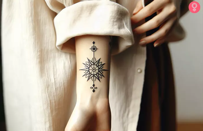 A woman with a minimalist sun compass tattoo on her wrist