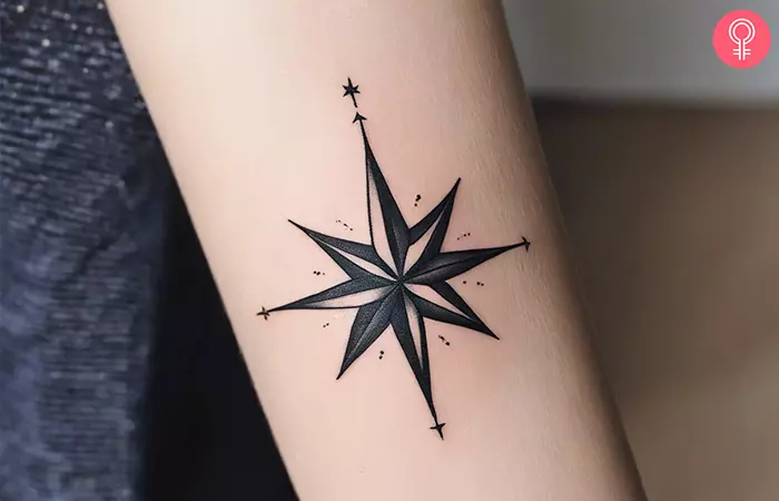 A woman with a minimalistic star compass tattoo on her forearm