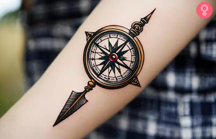 A woman with a traditional compass and arrowhead tattoo on her forearm