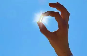 Person holding a vitamin D capsule in the sunlight