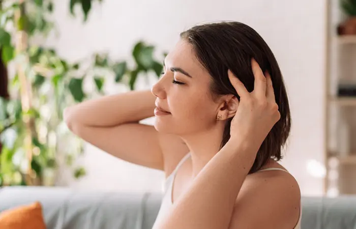 A woman applying hair oil on her head