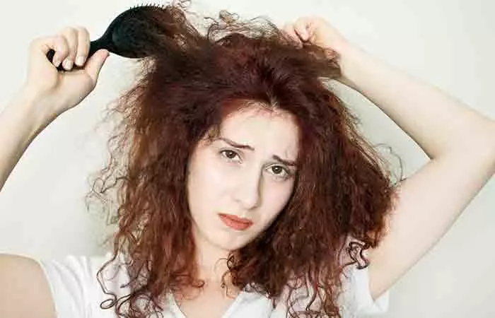 Woman struggling with detangling her dry and frizzy hair