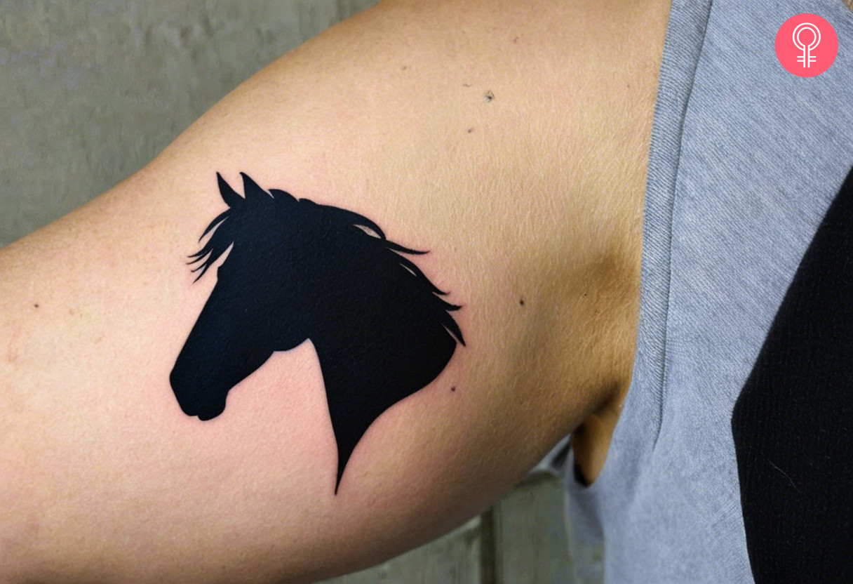 A horse silhouette tattoo on the inner bicep