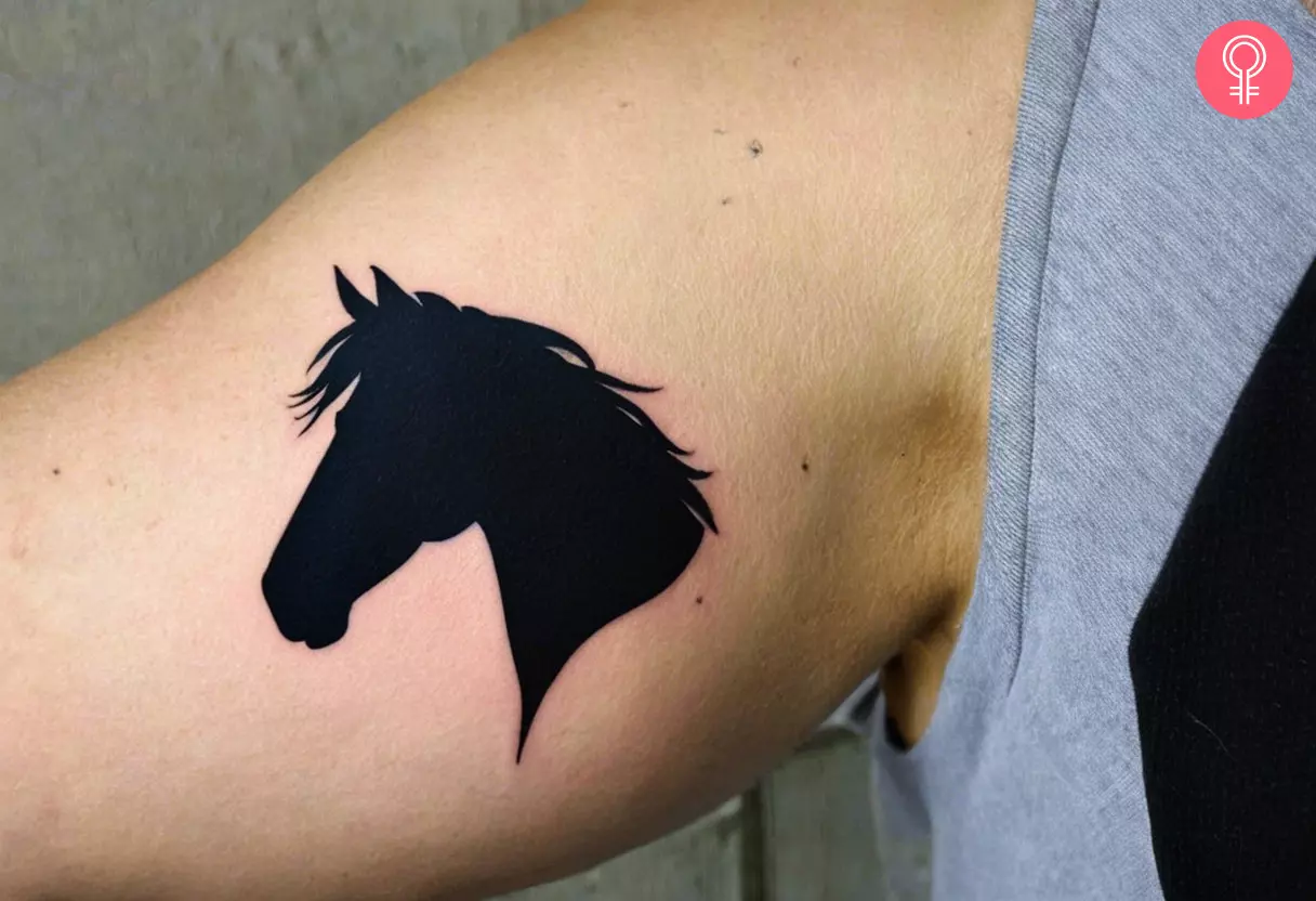 A horse silhouette tattoo on the inner bicep