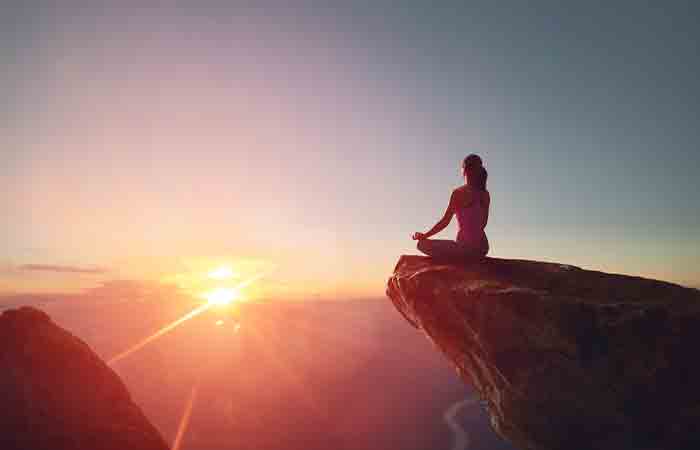 Woman practicing super brain yoga facing the rising sun