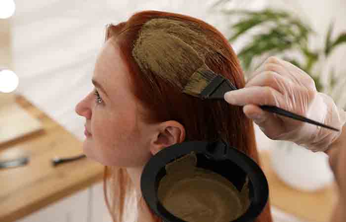 Woman having henna applied to her hair by a professional