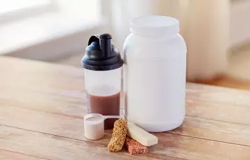 Bottle of whey protein shake, protein bars, jar of whey powder