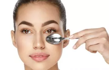 Woman uses cold spoon to get rid of eye bags.