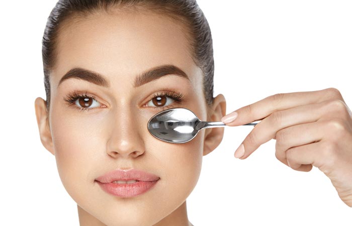 Woman uses cold spoon to get rid of eye bags.