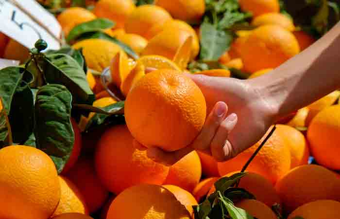 Close-up of a woman picking fresh mandarin oranges