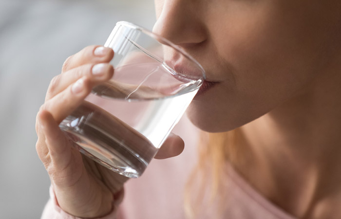 Close up of a woman drinking a glass of water.