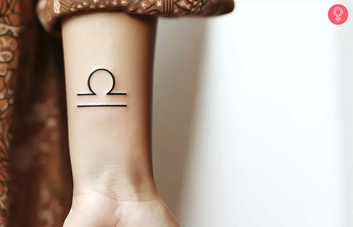 A woman with a Libra glyph tattoo on her wrist