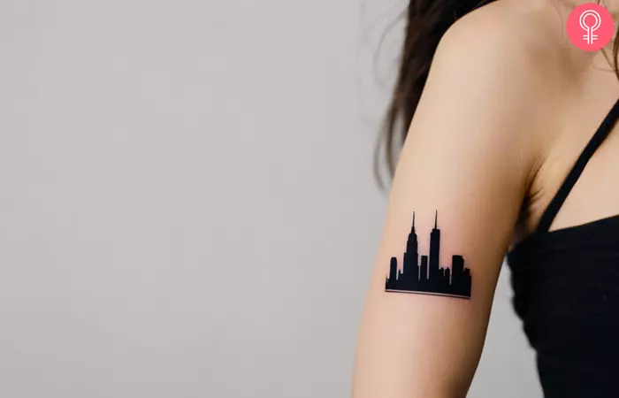 A cityscape barcode tattoo featuring skyscrapers in all-black ink