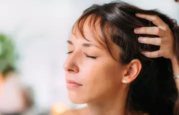 Woman massaging her hair with oil to prevent sweating-related hair loss
