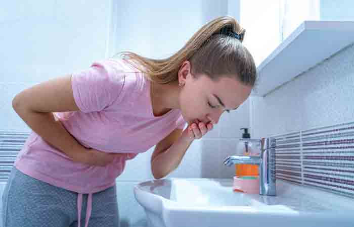Woman experiencing nausea and throwing up in the bathroom.