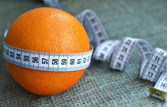 Mandarin orange wrapped in measuring tape symbolizing weight loss.