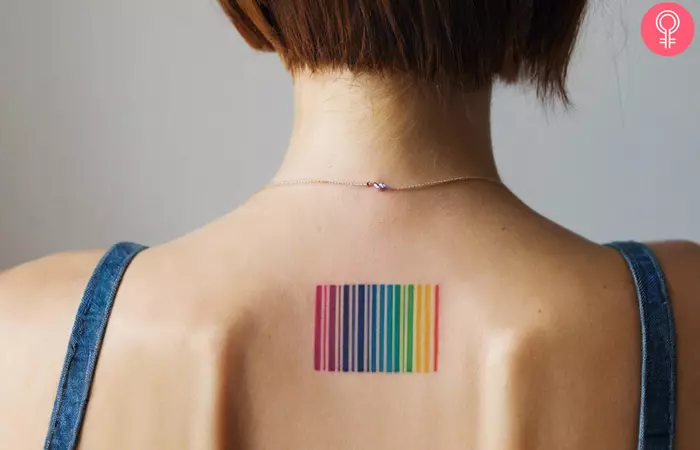 A colorful rainbow barcode tattoo on the upper back