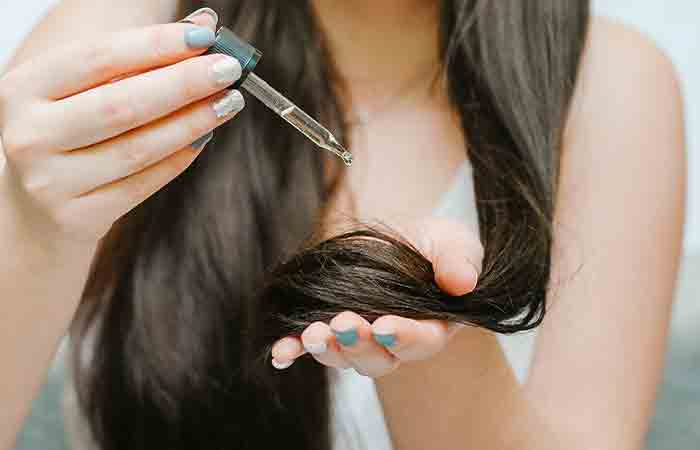 Женщина наносит кунжутное масло и масло брингараджа для роста волос