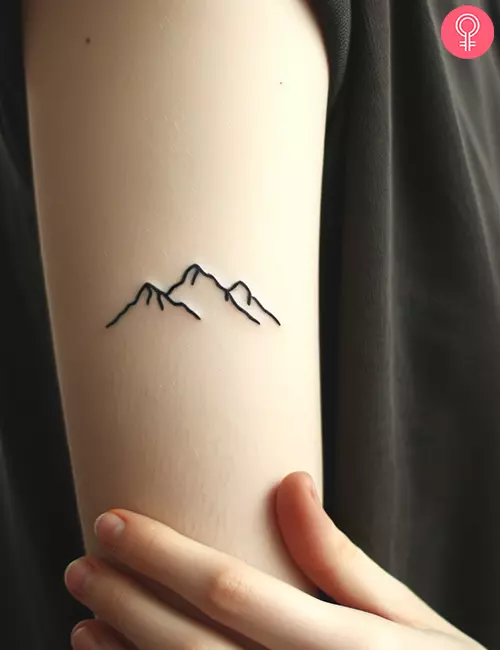 Simple mountain tattoo on the upper arm of a woman