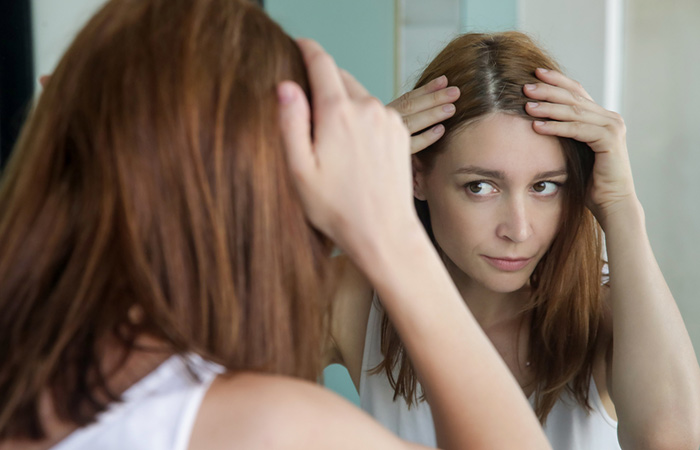 Woman examining her scalp in the mirror 