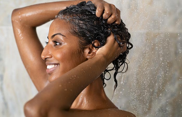 Woman washing her hair to prevent sweating-related hair loss