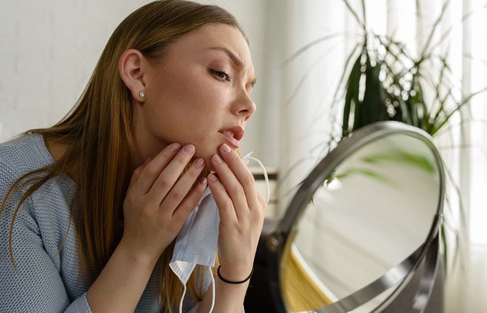 Woman checking her chin acne in the mirror